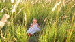 Cute baby in a white dress sitting in tall grass