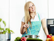 Young woman cooking in her kitchen, stiring in a pan