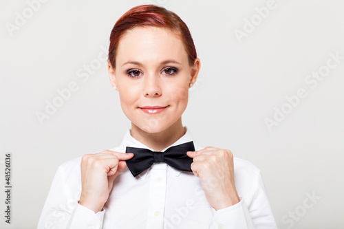 Photo: beautiful young waitress holding bow tie and smiling beautiful young waitress holding bow tie and smiling