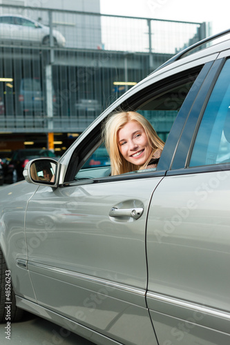 Photo: Woman back her car on a parking level Woman back her car on a parking level