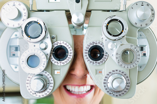 Photo: Junge Frau am Phoropter zum Sehtest Junge Frau am Phoropter zum Sehtest