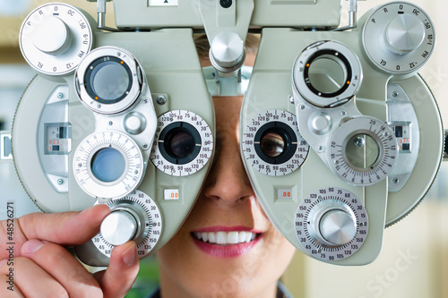 Photo: Junge Frau am Phoropter zum Sehtest Junge Frau am Phoropter zum Sehtest