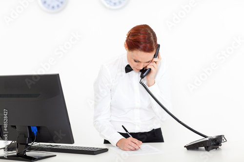 Photo: modern hotel receptionist talking on the phone at reception modern hotel receptionist talking on the phone at reception