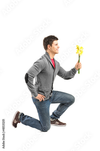 Photo: A male kneeling and holding a daffodil flower A male kneeling and holding a daffodil flower