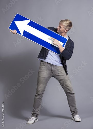 Photo: Confident man holding direction arrow sign. Confident man holding direction arrow sign.