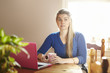 Young woman sitting at table with laptop looking confused
