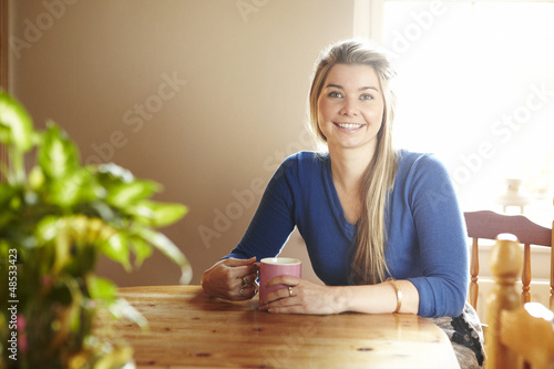 Photo: Young woman sitting at table smiling Young woman sitting at table smiling