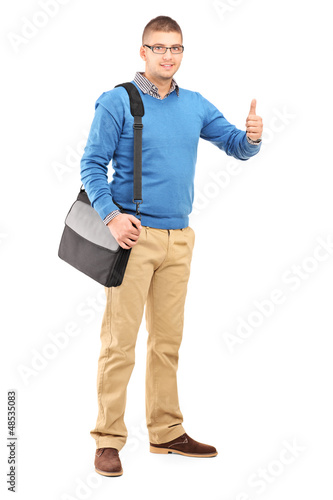 Photo: Full length portrait of a young man with a shoulder bag giving a Full length portrait of a young man with a shoulder bag giving a