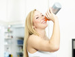 Active woman drinking water bootle in the kitchen