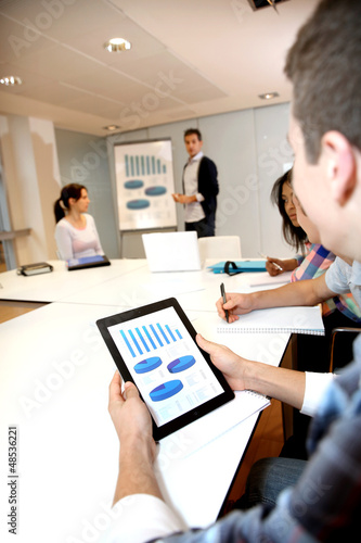 Photo: College student using tablet in class during presentation College student using tablet in class during presentation