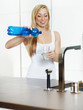 Woman infusing a drinking glass with water in her kitchen