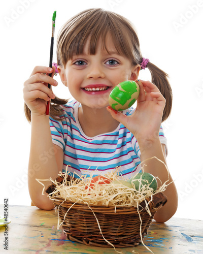 Photo: a happy little girl painting easter eggs - white background a happy little girl painting easter eggs - white background