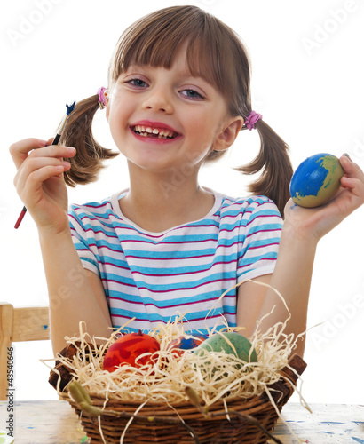 Photo: a happy little girl coloring easter eggs - white background a happy little girl coloring easter eggs - white background