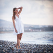 Photo: Young woman on the beach enjoying a warm summer evening Young woman on the beach enjoying a warm summer evening