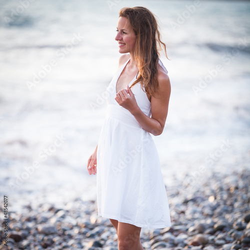 Photo: Young woman on the beach enjoying a warm summer evening Young woman on the beach enjoying a warm summer evening