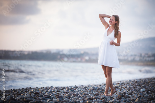 Photo: Young woman on the beach enjoying a warm summer evening Young woman on the beach enjoying a warm summer evening