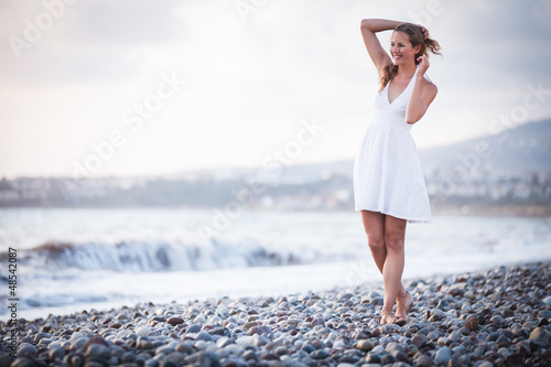 Photo: Young woman on the beach enjoying a warm summer evening Young woman on the beach enjoying a warm summer evening