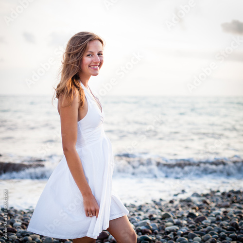 Photo: Young woman on the beach enjoying a warm summer evening Young woman on the beach enjoying a warm summer evening