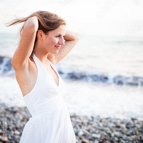 Photo: Young woman on the beach enjoying a warm summer evening Young woman on the beach enjoying a warm summer evening