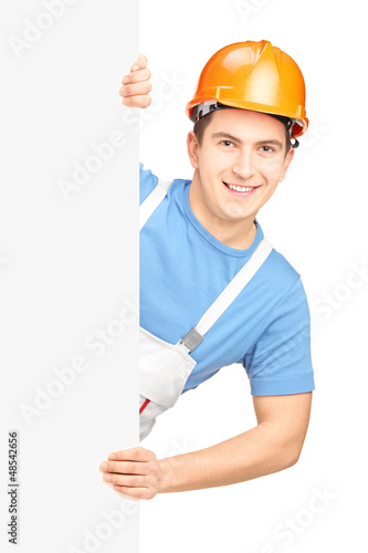 Photo: A male worker with helmet posing behind a blank panel A male worker with helmet posing behind a blank panel