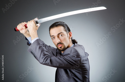 Photo: Angry businessman with sword in dark room Angry businessman with sword in dark room