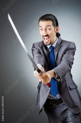 Photo: Angry businessman with sword in dark room Angry businessman with sword in dark room