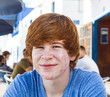 smart boy in puberty sitting on an outdoor table in the village