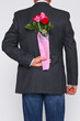 Bunch of roses behind a mans back.