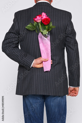 Photo: Bunch of roses behind a mans back. Bunch of roses behind a mans back.