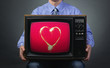 Foto: Retro TV featuring sparkling heart in the hands of men. Retro TV featuring sparkling heart in the hands of men.