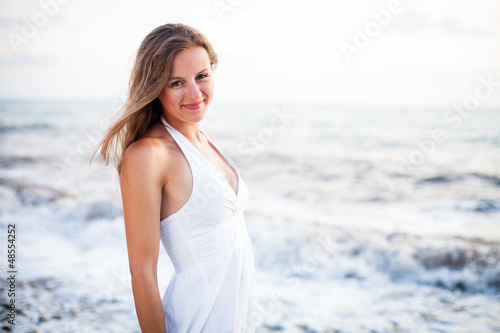 Photo: Young woman on the beach enjoying a warm summer evening Young woman on the beach enjoying a warm summer evening