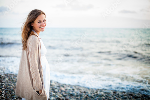 Photo: Young woman on the beach enjoying a warm summer evening Young woman on the beach enjoying a warm summer evening