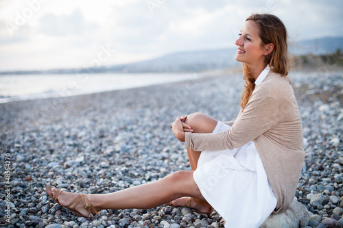 Photo: Young woman on the beach enjoying a warm summer evening Young woman on the beach enjoying a warm summer evening