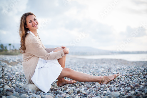 Photo: Young woman on the beach enjoying a warm summer evening Young woman on the beach enjoying a warm summer evening