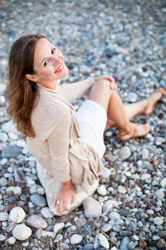 Photo: Young woman on the beach enjoying a warm summer evening Young woman on the beach enjoying a warm summer evening