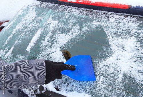 Photo: Hand scraping ice from the car window in winter time Hand scraping ice from the car window in winter time