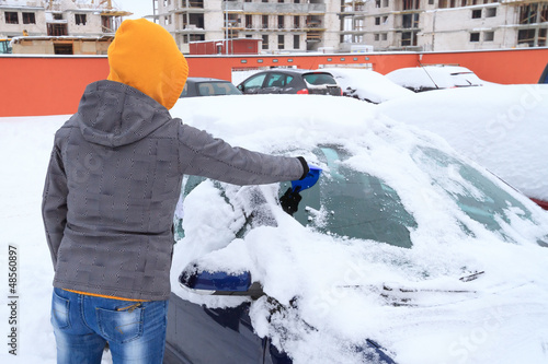 Photo: Woman scraping ice from the car window in winter time Woman scraping ice from the car window in winter time