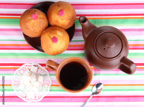 Photo: Top view of cup of tea and teapot on colorful tablecloths Top view of cup of tea and teapot on colorful tablecloths