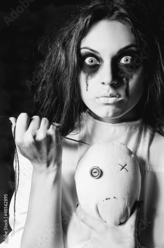 Photo: Horror scene: the strange crazy girl with moppet doll and needle Horror scene: the strange crazy girl with moppet doll and needle