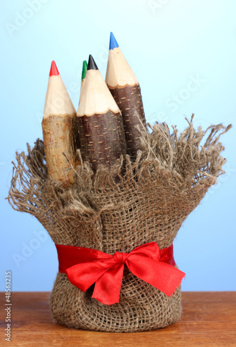 Photo: Colorful wooden pencils on wooden table on blue background Colorful wooden pencils on wooden table on blue background