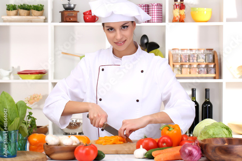 Photo: Young woman chef cooking in kitchen Young woman chef cooking in kitchen
