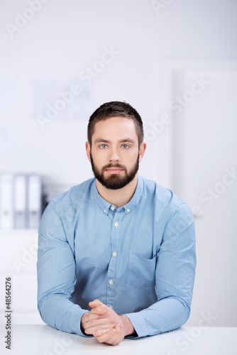 Photo: junger mann im büro schaut ernst junger mann im büro schaut ernst