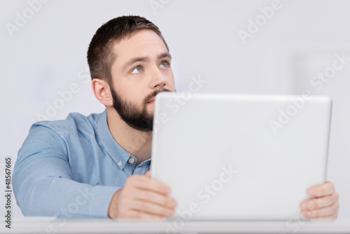 Photo: junger mann am laptop schaut nach oben junger mann am laptop schaut nach oben