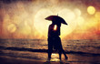 Couple kissing under umbrella at the beach in sunset. Photo in o