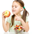 Little girl choosing between apples and sweets
