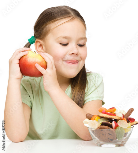Photo: Little girl choosing between apples and sweets Little girl choosing between apples and sweets