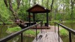 Bridge to summer house on small island on pond in grove