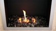 Tongues of flame go through slot in plate with stones around it