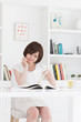 部屋で雑誌を読む若い女性