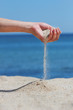Foto: Hand throws sand on the seashore Hand throws sand on the seashore